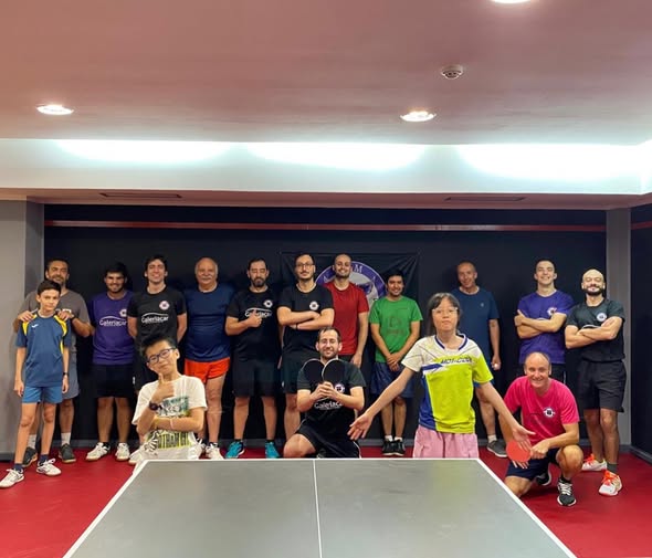 Grupo de atletas e praticantes do CTM Coimbra junto a uma mesa de ténis de mesa